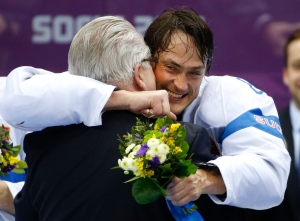 Teemu Selanne of Finland (8) hugs the presenter after receiving his medal after the men's bronze medal ice hockey game at the 2014 Winter Olympics, Saturday, Feb. 22, 2014, in Sochi, Russia. (AP Photo/Julio Cortez)