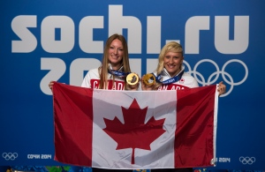 Kaillie Humphries, right, and Heather Moyse, bobsleigh gold medalists, pose with the Canadian flag as they are introduced as the flag bearers for the closing ceremonies at the Sochi Winter Olympics Sunday, February 23, 2014 in Sochi. THE CANADIAN PRESS/Paul Chiasson