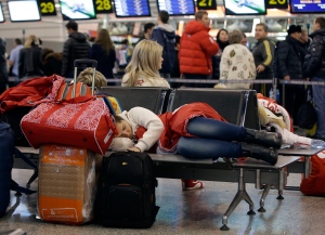 A passenger sleeps while waiting for a flight at the airport following the 2014 Winter Olympics Monday, Feb. 24, 2014, in Sochi, Russia. (AP Photo/Darron Cummings)