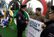 Activist David Khakim is approached by two police officers after pulling out a banner protesting a prison sentence for a local environmentalist in front of the Olympic rings Monday, Feb. 17, 2014, in central Sochi, Russia. (AP Photo/David Goldman)