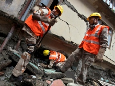 Members of Indian National Disaster Response Force search for a body, believed to be under the rubble of a school building, damaged in a 6.9-magnitude earthquake in Chungthang, India, Thursday, Sept. 22, 2011. Rescuers in helicopters on Thursday reached some of the villages in India's remote northeast that were cut off by a powerful earthquake that rattled the Himalayan region last weekend. (AP Photo/Altaf Qadri)