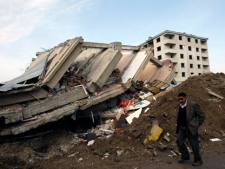 A man walks by a destroyed building in Ercis, eastern Turkey, Wednesday, Oct. 26, 2011. Excavators with heavy equipment began clearing debris from some collapsed buildings in Ercis after searchers removed bodies and determined there were no other survivors. The 7.2-magnitude quake Sunday has killed at least 461 people and injured over 1,350. (AP Photo/Burhan Ozbilici)