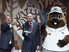 Environment Minister Peter Kent, centre, flips a coin with Alan Latourelle, Parks Canada CEO, and Parka, Parks Canada's mascot, during the new Parks Canada centennial loonie unveiling Friday, Oct. 7, 2011, at the Canadian Museum of Civilization in Gatineau, Quebec. (The Canadian Press Images PHOTO/Parks Canada)