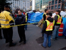 Police officers and city officials stand at an entrance to the Occupy Vancouver site in downtown in Vancouver, B.C., on Saturday November 5, 2011. A woman at the Occupy Vancouver camp died Saturday afternoon after being discovered in an "unresponsive" condition, police said. The woman in her 20s was discovered in a tent by another protester. Paramedics took her to hospital where she was pronounced dead, police said.THE CANADIAN PRESS/Darryl Dyck