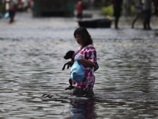 A Thai woman carries her pet dog as she wades through floodwaters with a packet of food distributed from soldiers at a flooded neighborhood in Bangkok, Thailand, Wednesday, Nov. 9, 2011. The flooding began in late July and the water has reached parts of Bangkok, where residents are frustrated by government confusion over how much worse the flooding will get. (AP Photo/Altaf Qadri)