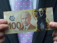 Bank of Canada Governor Mark Carney holds a new $100 bill as he unveils the new polymer bank notes in $50 and $100 denominations at the Bank of Canada in Ottawa on Monday, June 20, 2011. (THE CANADIAN PRESS/Sean Kilpatrick)