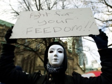 An Occupy Toronto protester holds a sign as City of Toronto bylaw officers place a new batch of eviction notices on tents and structures at the Occupy Toronto grounds in St. James Park in Toronto on Monday, Nov. 21, 2011. (THE CANADIAN PRESS/Nathan Denette)