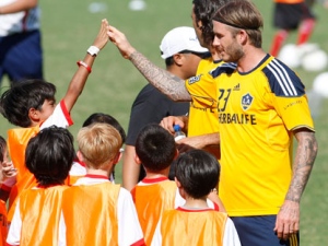 British soccer player David Beckham of the Los Angeles Galaxy exchanges high-fives to Filipino children while conducting football clinic lat the Rizal Memorial Football Stadium Friday Dec. 2, 2011 in Manila, Philippines. Beckham is here for a friendly game against the Philippines' Azkals team, the second leg of his team's 3-country-tour that included Indonesia and Australia. (AP Photo/Bullit Marquez) 