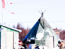 The remains of a Canadian flag can be seen flying over a building in Attawapiskat, Ont. on November 29, 2011. The federal government is forcing the troubled Attawapiskat First Nation to pay a private-sector consultant about $1,300 a day to run its finances - even though the government's own assessments say the third-party management system is not cost-effective. THE CANADIAN PRESS/Adrian Wyld