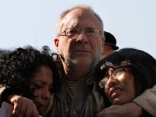 Javier Sicilia, center, a Mexican poet turned activist and leader of the "Peace with Justice and Dignity" movement, hugs Coral Bautista, left, and Victoria Alarcon, relatives of people abducted or killed by alleged drug gangs during a protest to demand peace and justice in Mexico City, Sunday, Dec. 11, 2011. (AP Photo/Marco Ugarte)
