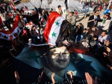 Syrians surround a large poster showing Syria's President Bashar Assad, during a rally in Damascus, Syria, Friday, Dec. 16, 2011. Syrian security forces opened fire on anti-government protesters after Friday prayers at several locations around the country, while the army sent reinforcements into a southern area where military defectors recently launched deadly attacks on regime troops. (AP Photo/Muzaffar Salman)