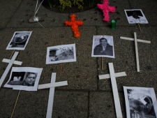 Crosses and pictures of people killed or abducted by alleged drug gangs are placed on a sidewalk during a protest to demand peace and justice in Mexico City, Sunday, Dec. 11, 2011. (AP Photo/Marco Ugarte)