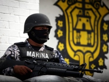A masked Mexican navy marine guards outside of a police station after the entire police force was disbanded in the Gulf port city of Veracruz, Mexico, Wednesday Dec. 21, 2011. The Veracruz state government said the decision is part of an effort to root out police corruption and start from zero in the state's largest city. The navy will be in charge of patrolling the city for the time being. (AP Photo/Felix Marquez)