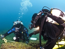 In a June 13, 2011 photo, divers from the university and the National Geographic Society examine boulders on the bottom of Lake Huron near Alpena, Mich., that were used as caribou drive lanes by prehistoric hunters. (AP Photo/Thunder Bay National Marine Sanctuary via the University of Michigan News Service, Tane Casserly)