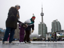Kathy Ponesse, left, and Richard Ponesse, far right, skate with their three-year-old granddaughter Julia Dubrick, centre, at the Harbourfront rink in Toronto on Tuesday, Dec. 27, 2011. (THE CANADIAN PRESS/Pawel Dwulit)