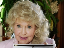 In this Jan. 8, 2009, photo, Donna Douglas, who starred in the television series "The Beverly Hillbillies," poses with a photo from the show in Baton Rouge, La. (AP Photo/Bill Haber)