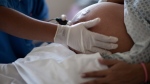 A pregnant woman is examined as she waits to give birth at a hospital on July 25, 2012. (Felipe Dana/AP)