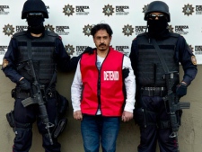 Baltazar Saucedo Estrada, alias "El Mataperros," center, is presented to the media as he is guarded by members of the new Fuerza Civil police force in Monterrey, Mexico, Thursday Jan. 6, 2012. According to police authorities, Sauceda is an alleged member of the Zetas drug cartel and is considered the mastermind behind a casino fire that killed 52 people on Aug. 25, 2011 in Monterrey. (AP Photo/Hans-Maximo Musielik)