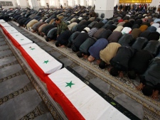 Syrian mourners pray in front of the coffins of 11 Syrian police officers who were killed in an explosion in the Midan neighborhood of Damascus on Friday, during a mass funeral at Al-Hassan mosque, Damascus, Syria, Saturday, Jan. 7, 2012. Thousands of regime backers massed at a mosque in the Syrian capital Saturday for funeral prayers for policemen killed in a Damascus bombing, as the government vowed to respond with an "iron fist" to security threats. (AP Photo/Muzaffar Salman)