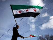 A Syrian immigrant waves Bulgarian and the revolutionary Syrian flag, during a rally against the regime of Syrian President Bashar al-Assad in front of the Syrian embassy in Sofia, on Sunday, Jan. 8, 2012. Syrian opposition groups say the death toll has risen beyond 6,000 and government forces continue to kill protesters despite the presence of Arab League monitors. (AP Photo/Valentina Petrova))