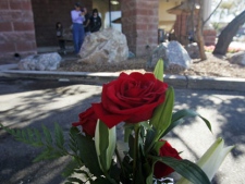 People gaze at a small memorial plaque on a rock at the Safeway market on Saturday, Jan. 7, 2012, to commemorate the victims of the mass shooting on Jan. 8, 2011, in Tucson, Ariz. The one-year anniversary of the shooting of Rep. Gabrielle Giffords in the parking lot of the grocery store is Sunday. Arizona is marking the event with a series of events, including community-wide bell-ringing at the moment of the attack, speeches on behalf of the victims, and an evening candlelight vigil that Giffords will attend. (AP Photo/Arizona Daily Star, Rick Wiley) 