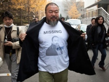 In this Nov. 16, 2011 photo, Chinese dissident artist Ai Weiwei opens his jacket to reveal a shirt bearing his portrait as he walks into the Beijing Local Taxation Bureau. (AP Photo/Andy Wong)