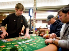 In this photo taken Saturday, Dec. 17, 2011, Kevin Hildebrandt, centre, and Vaughn Kercher play poker at dealer Nate Wheatley's table at the Oak Tree Casino in Woodland, Wash. (AP Photo/The Columbian, Steven Lane)