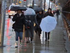 Pedestrians shield themselves from rain while walking along Queen Street West on Friday, Jan. 27, 2012.