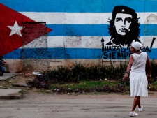 A santera looks back while crossing the street where a wall is covered with a mural of the Cuban flag and an image of Cuba's revolutionary hero Ernesto "Che" Guevara in Havana, Cuba, Friday Jan. 27, 2012. After economic reforms by President Raul Castro were endorsed by the communist congress in mid-2011, the Communist Party of Cuba (PCC) held a party conference this weekend. (AP Photo/Franklin Reyes)