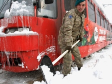 Turkish soldiers members of the European Union Force in Bosnia and Herzegovina, EUFOR, shovel snow from the tracks around a frozen tram as they work to normalize public transport in Bosnian capital of Sarajevo, on Sunday, Feb. 5, 2012. Bosnia's government declared a state of emergency in its capital on Saturday after Sarajevo was paralyzed by snow. (AP Photo/Amel Emric)