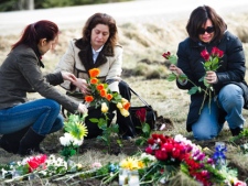 Samaria Enamorado (right), whose husband Juan Castillo died in Monday's fatal crash, and relatives Lourdes Gray (centre) and Ana Enamorado (left) lay flowers at the scene of the crash in Hampstead, Ont., on Wednesday, Feb. 8, 2012. A van carrying 13 migrant workers ran a stop sign before it was broadsided by a truck and the "violent" impact killed 11 people at a rural intersection, police said Wednesday. (THE CANADIAN PRESS/Nathan Denette)