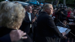 A hand is rested on Diane Ford's shoulder as her son, Doug Ford speaks to the media outside his mother's Etobicoke home on Friday September 12, 2014. Toronto Mayor Rob Ford's brother says he is running for mayor in order to carry on the work the two of them started in the past four years.(Chris Young/The Canadian Press)