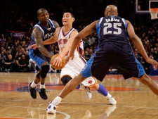 New York Knicks' Jeremy Lin, center, drives through Dallas Mavericks' Vince Carter, right, and Dominique Jones during the first half of an NBA basketball game in New York, Sunday, Feb. 19, 2012. (AP Photo/Seth Wenig)