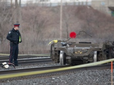 A police officer stands beside a set of train wheels that fell off a Via Rail train after a derailment in Burlington, Ont., on Sunday, Feb. 26, 2012. (THE CANADIAN PRESS/Pawel Dwulit)