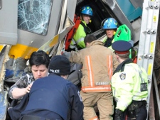 Emergency crew help passengers out of a train wreck in Burlington, Ont., on Sunday, Feb. 26, 2012. Three Via Rail employees were killed in the crash. (THE CANADIAN PRESS/David Ritchie)