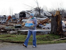 A woman carries a box of water on the street in Marysville, Ind., Saturday, March 3, 2012. Massive thunderstorms, predicted by forecasters for days, threw off dozens of tornadoes as they raced Friday from the Gulf Coast to the Great Lakes. Twisters crushed blocks of homes, knocked out cellphones and landlines, ripped power lines from broken poles and tossed cars, school buses and tractor-trailers onto roads made impassable by debris. (AP Photo/Nam Y. Huh)