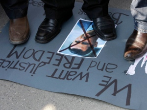 Protesters stand on a crossed out picture of Syrian President Bashar Assad during a rally against his regime in front of the Syrian embassy in Belgrade, Serbia, Tuesday, March 6, 2012. (AP Photo/Darko Vojinovic)