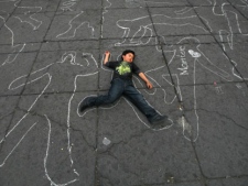 A boy lies on the floor among silhouettes representing people allegedly killed by soldiers during Mexico's drug war during a protest organized by the National Regeneration Movement, MORENA, at the Zocalo central square in Mexico City on Sunday March 4, 2012. (AP Photo/Marco Ugarte)