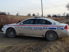 A Durham police car is parked near a farmer's field in Sunderland, Ont. where two bodies were found in the trunk of an abandoned car. (Tom Podolec/CTV)
