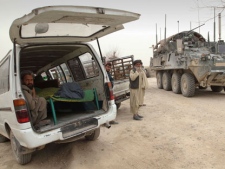 An armored military vehicle from the NATO-led International Security Assistance Force (ISAF) is seen at right, as the covered body of a person who was allegedly killed by a U.S. service member is seen inside a minibus in Panjwai, Kandahar province south of Kabul, Afghanistan, Sunday, March 11, 2012. A U.S. service member walked out of a base in southern Afghanistan before dawn Sunday and started shooting Afghan civilians, according to villagers and Afghan and NATO officials. Villagers showed an Associated Press photographer 15 bodies, including women and children, and alleged they were killed by the American. (AP Photo/Allauddin Khan)