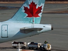 An Air Canada employee moves baggage on the tarmac at Halifax Stanfield International Airport in Enfield, N.S. on Thursday, March 8, 2012. Members of the international Association of Machinists and Aerospace Workers, the largest unionized workforce at Air Canada, say they will begin a strike early next week unless there is a new contract. (THE CANADIAN PRESS/Andrew Vaughan)
