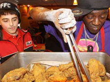 Rapper-turned-reality show star William Drayton, better known as Flavor Flav, right, serves the first batch of chicken he cooked just minutes earlier to 12-year-old Nick Cimino Jr., Monday Jan. 24, 2011 at Flav's Fried Chicken in Clinton, Iowa. (AP Photo/The Quad City Times, Kevin E. Schmidt)