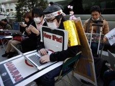Ryo Takahashi wearing a samurai wig browses internet as he and others wait in a queue to buy a new iPad outside an Apple Store in Tokyo, Thursday, March 15, 2012, one day before the the new iPad goes on sale Friday. (AP Photo/Shizuo Kambayashi)