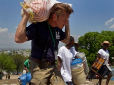 In this April 10, 2010 file photo, U.S. actor Sean Penn carries the belongings of a person displaced by the earthquake as people are relocated from the Petion ville Golf Club to a new camp, Corail-Cesselesse, in Port-au-Prince, Haiti. Penn is being honored by a group of Nobel laureates for his relief work in Haiti following the country's devastating January 2010 earthquake. Penn is to receive the 2012 Peace Summit Award at the 12th World Summit of Nobel Peace Laureates at an event in Chicago in April 2012 and is expected to draw such luminaries as Poland's Lech Walesa and the Dalai Lama. (AP Photo/Ramon Espinosa)