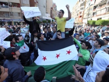 Anti-Syrian regime protesters hold Syrian revolution flags and chant slogans against Syrian President Bashar Assad during a demonstration after Friday prayers in Beirut, Lebanon, Friday, March 23, 2012. The placard at center left in Arabic, reads, "a giant has awakened."(AP Photo/Bilal Hussein)