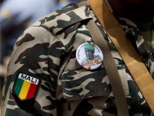 A soldier wears a button bearing the image of coup leader Capt. Amadou Haya Sanogo with the words 'President, CNRDRE,' the French acronym by which the ruling junta is known, as he stands guard at junta headquarters in Kati, outside Bamako, Mali Sunday, April 1, 2012. (AP Photo/Rebecca Blackwell)
