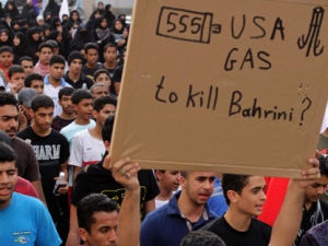 Bahraini anti-government protesters in Bilad al-Qadeem, Bahrain, on the edge of the capital of Manama, march toward the nearby U.S. Embassy on Tuesday, April 10, 2012. The sign refers to U.S.-made tear gas canisters that have been used heavily by riot police during the unrest. (AP Photo/Hasan Jamali)