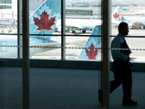 A person walks by Air Canada planes at Toronto's Pearson airport Friday, April 13, 2012. Air Canada says an "illegal job action" by some of its pilots caused cancellations and delays across the country. (THE CANADIAN PRESS/Michelle Siu)