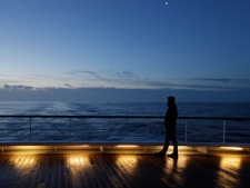 A passenger of MS Balmoral Titanic memorial cruise ship, gazes out to the Atlantic Ocean, following a memorial service, marking the 100-year anniversary of the Titanic disaster, in the early hours of Sunday, April 15, 2012. The Titanic passenger liner was built in Belfast, and sank in the North Atlantic Ocean on its maiden voyage from England to New York, USA, in the early hours of April 15, 1912, after colliding with an iceberg and over 1,500 people perished in the sinking. (AP Photo/Lefteris Pitarakis)