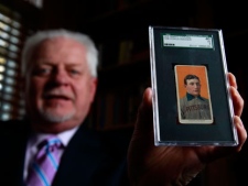 In this March 26, 2012, file photo, Bill Goodwin, a Missouri collectibles dealer, holds up a rare 1909 Honus Wagner baseball card in Sunset Hills, Mo. A New Jersey man, whose name has not been released, was the winning bidder for the rare baseball card _ at $1.2 million _ in an online auction that ended Friday, April 20, 2012. (AP Photo/Jeff Roberson, File)